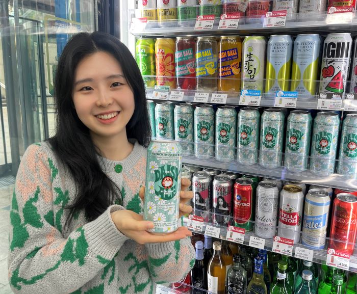 고객이 GS25에서 피스마이너스원의 디자인과 지드래곤 상징을 담은 ‘데이지에일’ 맥주를 들고 포즈를 취하고 있다. 사진=GS리테일