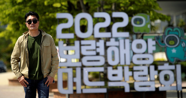 박람회 안내판 앞에서 포즈를 취하고 있는 김기정 총감독.출처=박재성 기자.