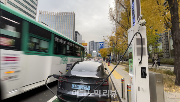 서울 태평로빌딩 앞 가로등형 전기차 충전기서 충전중인 테슬라 모델 3 바로 왼편에 버스가 지나가는 모습. 만약 이 사이에 운전자가 승하차를 했다면 안전사고까지 이어질 가능성이 존재한다. (사진=조재환 기자)