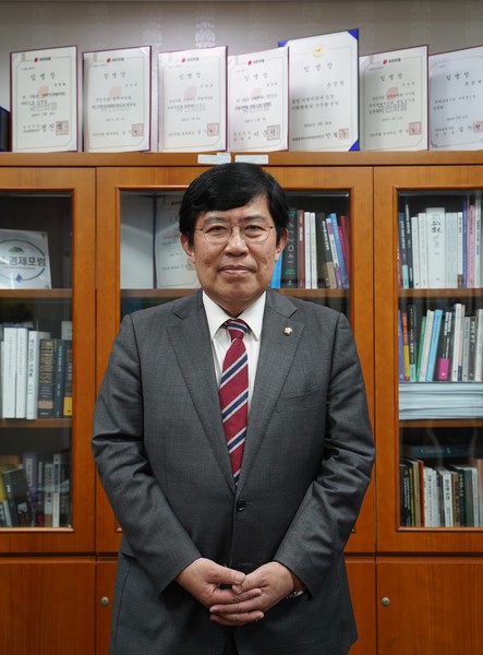 윤창현 국민의힘 의원은 테이블에 쌓인 자료와 함께 사진을 찍자는 요청을 ‘쑥스럽다’며 거절하고 책장 앞에 자세를 잡았다. 사진=강예슬 기자