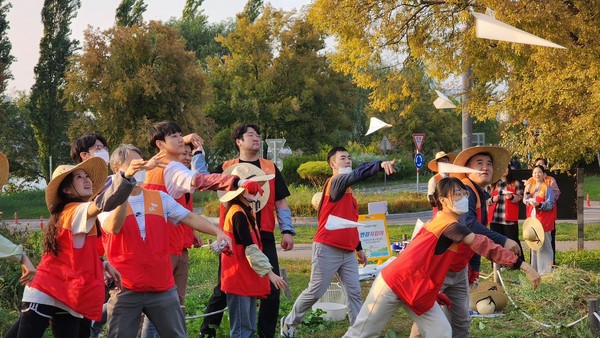 SK이노베이션 계열 구성원들이 물에 녹는 종이에 씨앗을 담은 ‘꽃씨 비행기’를 생태교란식물을 제거한 자리에 던지고 있다. 사진=SK이노베이션