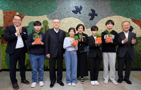 한화 김신연 사장(왼쪽 세번째)이 진잠초 학생들과 함께 공기정화를 위해 한화가 벽면에 조성한 모스월 앞에서 반려 식물을 들고 기념촬영을 하고있다. 사진=한화