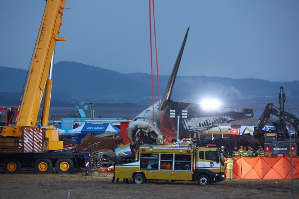 29일 오후 전남 무안군 무안국제공항에서 발생한 제주항공 여객기 충돌 폭발 사고 현장에서 대형 크레인이 파손된 기체 후미 부분을 옮기고 있다. 사진 = 연합뉴스.