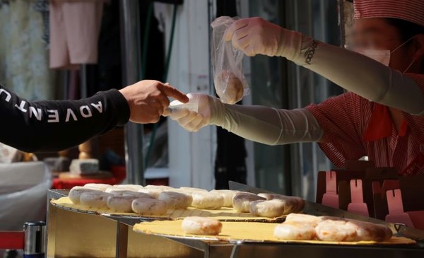 27일 서울 중구 남대문시장에서 한 시민이 간식거리를 구입하고 있다. 사진=연합뉴스