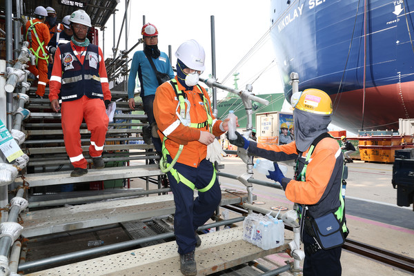 한화오션 안전관리자가 오후 쉬는 시간 휴식을 위해 하선하는 작업자들에게 얼음 생수를 전달하고 있다. 사진=한화오션