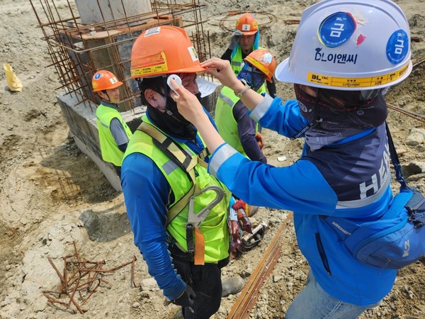 DL이앤씨 현장 안전보건관리자가 근로자의 체온을 측정하고 건강상태를 확인하고 있다. 사진=DL이앤씨