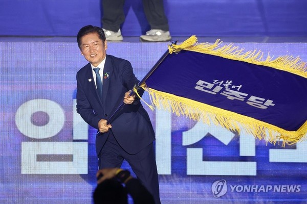 더불어민주당 정청래 신임 당대표가 2일 고양 킨텍스에서 열린 전국당원대회에서 김병기 당대표 직무대행 겸 원내대표로부터 받은 당기를 흔들고 있다. 사진=연합뉴스.