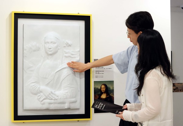 시각장애인을 위한 어두운 미술관 전시에 AI·3D프린팅 기술로 재현된 '모나리자'를 일반 관람객들이 실제로 만지며 감상하고 있다. 사진 제공=한국장애인문화예술원 이음센터.