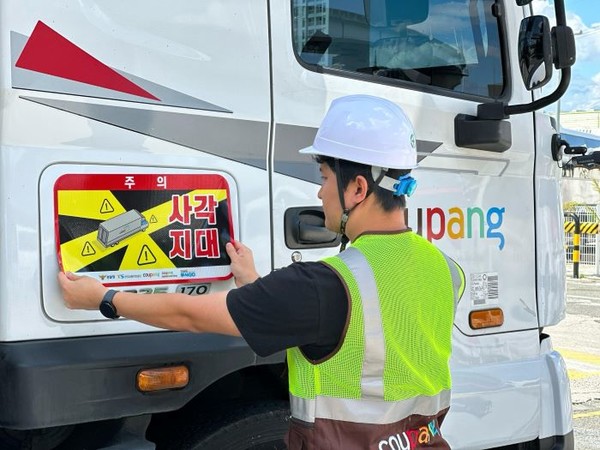 쿠팡·쿠팡로지스틱스서비스 대형 화물차에 ‘사각지대 주의’ 알림 표지를 부착하는 모습. 사진=쿠팡